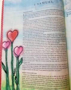 Bible journaling page in 1 Samuel decorated with heart-shaped pink flowers and green stems painted along the margin, creating a whimsical and faith-inspired floral design
